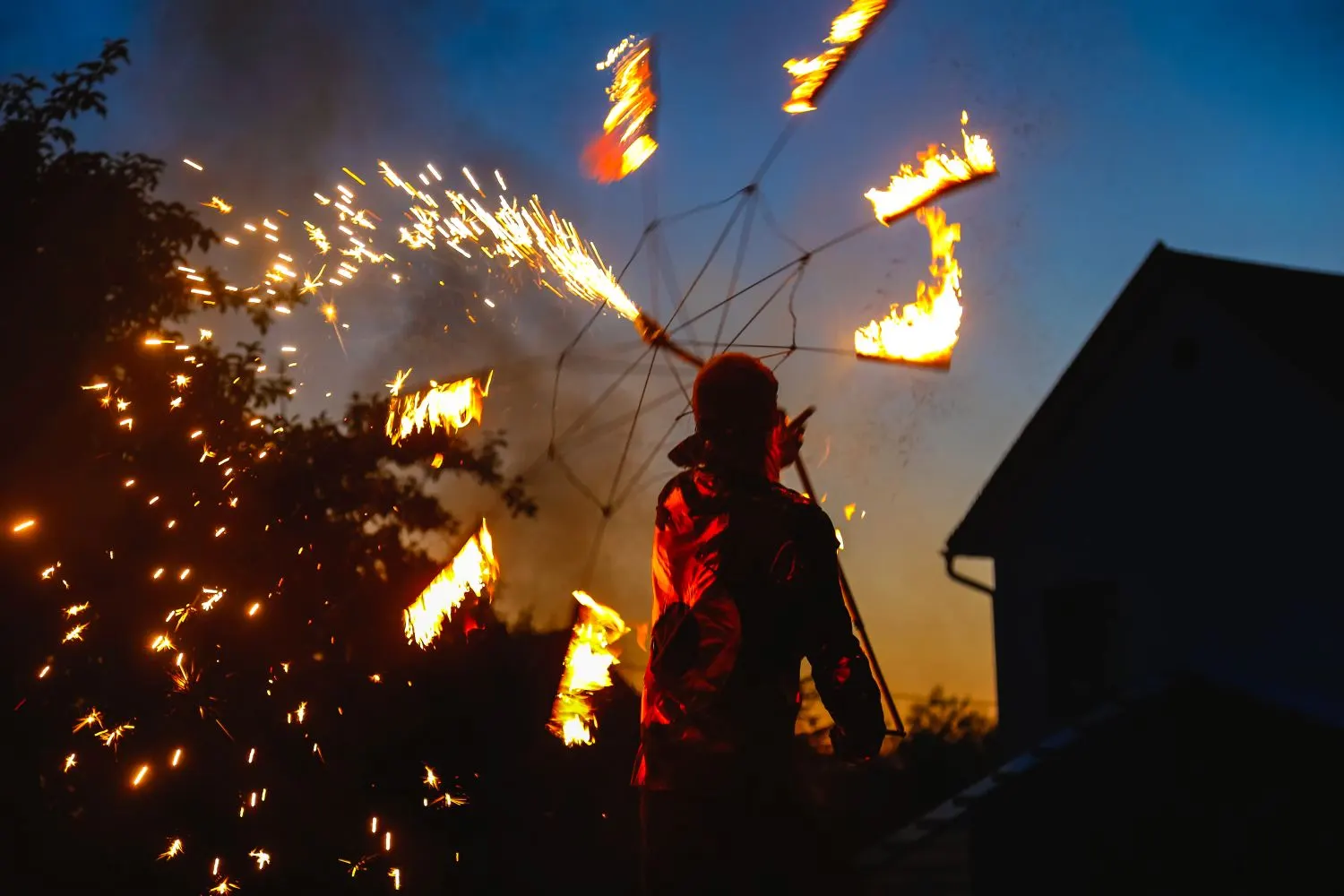 gepservices-precaucion-pirotecnia-vista-trasera-de-la-bailarina-de-fuego-por-la-casa-contra-el-cielo-durante-la-puesta-de-sol -